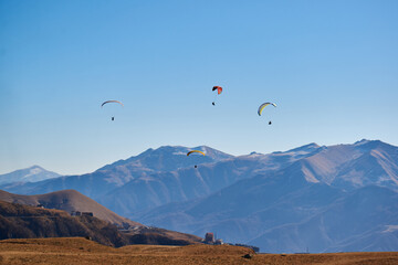 A few paragliders fly between the snow-capped mountains. extreme sports, freedom and beauty of...