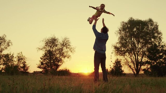 Dad plays with his son, throws up child with his hands in sky, outdoors. Child, superhero, fly. Happy Father, child, little boy have fun together in park, sun. Family game concept. Kid fatherhood