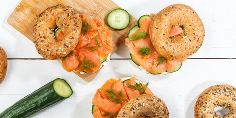 Bagel sandwich with salmon and cream cheese for breakfast on a wooden board from above panorama