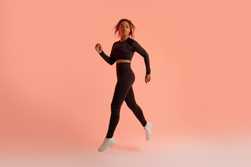 Fototapeta na wymiar Black female athlete jumping, running, exercising during training over neon studio background, full length