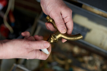 A man is holding an old brass faucet for a water pipe mixer