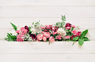 Spring or summer garden flowers. Pink and white assorted flower heads between white wooden background. Carnations hyacinth roses alstroemeria primrose floral arrangement. Holiday concept