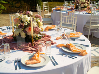 Beautiful outdoor wedding decoration in city. Candles and dried flowers and accessories with bouquets and glasses on table with linen tablecloth on newlywed table on green lawn