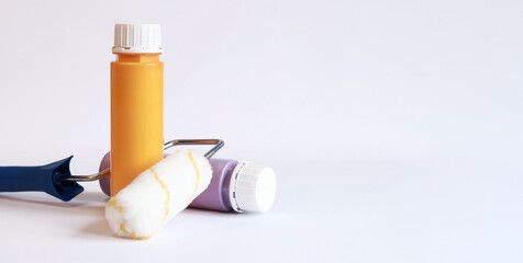 Interior renovation paint. Paint in plastic bottles and paint roller on a white background. Free space for text. Two bottles of acrylic paint, photo for banner