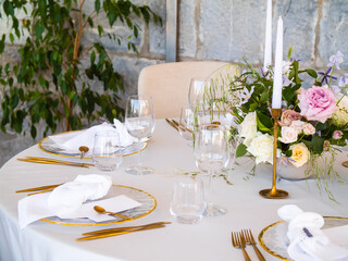 Table at luxury wedding reception event. Beautiful flowers on table and serving dishes and glasses and decoration
