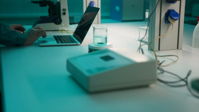 Woman hands, laptop at the chemical lab with flask, microscope, and other equipment . Stock footage. Medical laboratory.