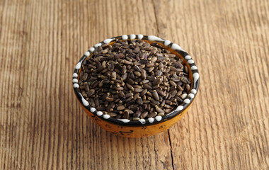 Heap of milk thistle seeds on the background of wooden texture. Selective focus.