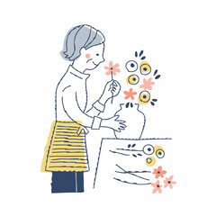 花瓶に花を生けているシニア女性