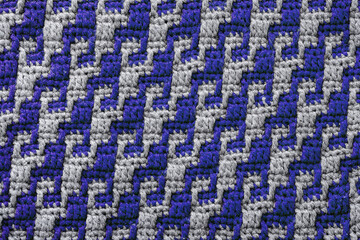Texture of crochet fabric with blue grey geometric pattern. Mosaic crochet background.