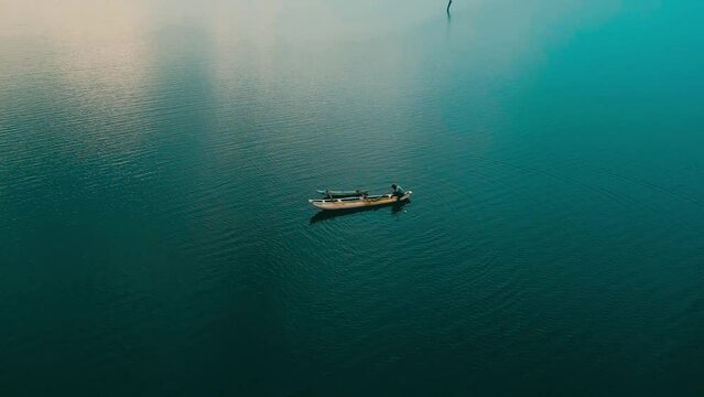 Aerial drone view of a wooden fishing boat sailing on a lake