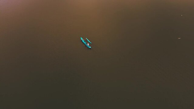 Aerial drone view of a evening wooden fishing boat sailing on a lake