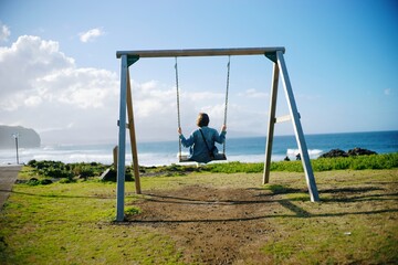 girl on a swing on the background of the ocean coast