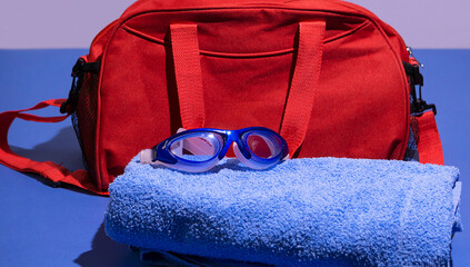 swimming goggles with a red bag and towel