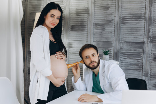 Female gynecologist working with pregnant woman in clinic. Doctor listening to heartbeat of patient