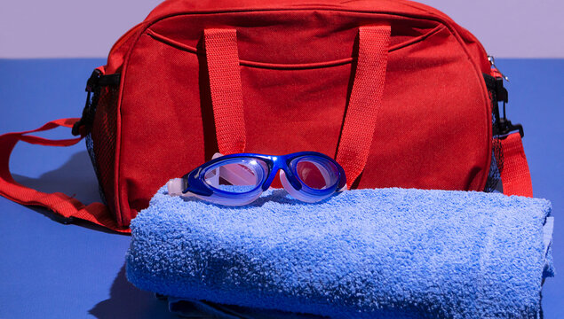 swimming goggles with a red bag and towel