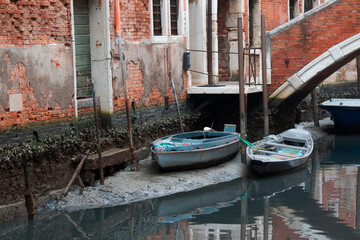 Boats in a canal in Venice with exceptionally low tide © rxlion