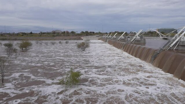 Water rushing over the dam at Tempe Town Lake in Tempe, Arizona with trees inundated by the water flow
