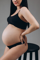 Portrait Of Happy Pregnant Woman In Lingerie With Smile Face Made Of Cream On Her Belly Posing Over Beige Background, Beautiful Young Expectant Female In Underwear Smiling At Camera.