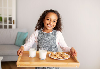 African Girl Holding Tray With Cookies And Milk At Home
