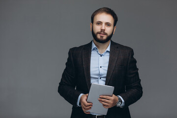 Attractive handsome businessman standing on grey background.