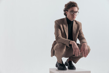 businessman squatting on wooden chair and looking away
