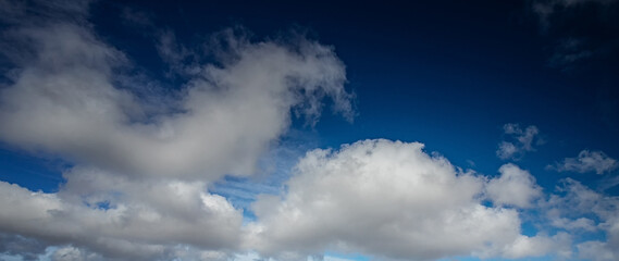 Naklejka na ściany i meble Błękitne niebo z białymi chmurami. Naturalne niebo jako tło. Piękne białe chmury na niebieskim niebie. Tekstura tło. Panoramicznie