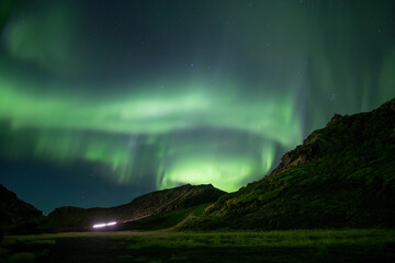 Car driving mountain road under Aurora borealis Iceland