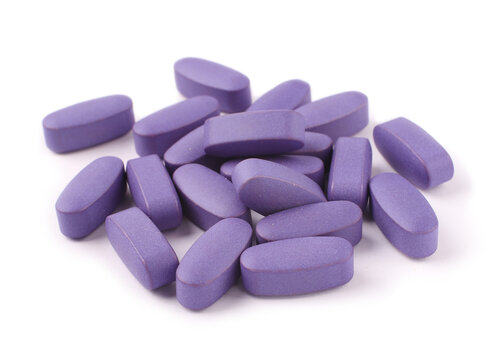 Purple pills on white background, close-up