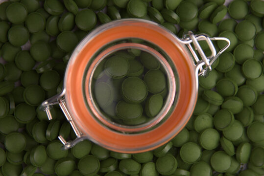 Green tablets of bio chlorella in a glass jar. A health-promoting dietary supplement rich in vitamins. Chlorella vulgaris.