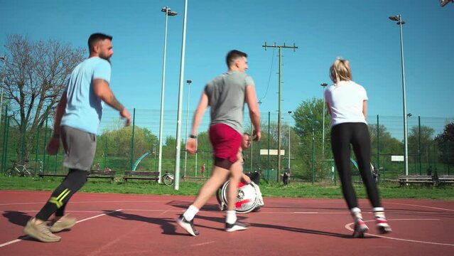 A physically challenged person play street basketball with his friends.	
