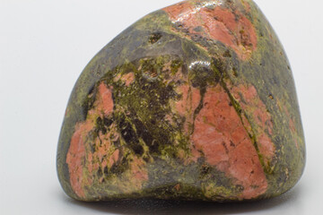Macro tumbled green and orange unakite jasper crystal, silicate chalcedony mineral variety, isolated on a white surface background  