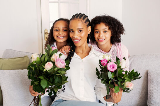 Cheerful Black Mother And Daughters Posing With Flowers At Home