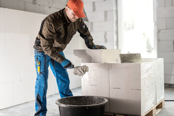 Scooping mortar with a spoon mason from the mortar bin. Internal insulation of buildings with mineral insulation panel.