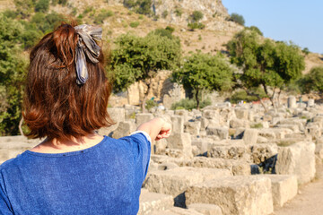 Fototapeta premium Woman archaeologist showing the ruins of historical artifacts with her hand in the ancient city.