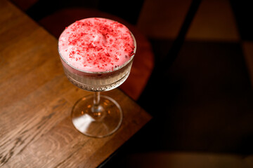 great top view of wine glass with foamy cocktail decorated with pink powder on table