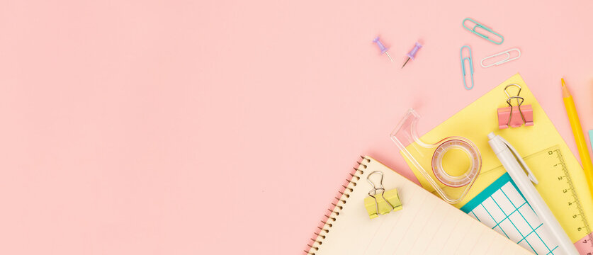Banner with stationery items for girls or women on light pink background. Back to school. Female Student's, pupil's or student's supplies. Office objects on pastel pink background