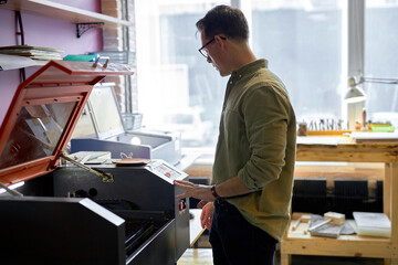 leathe crafting with laser engraving machine, close eup side view shot. copy space, guy learns to work with 3D printer
