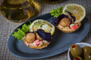 Tart with scallop and seafood decorated with slice of lemon and basil