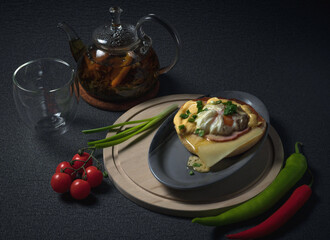 Breakfast with eggs benedict, fresh vegetables, tomatoes, peppers, green onion and tea in a glass teapot