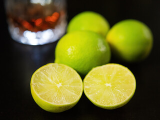 Tasty limes on the table with a glass of refreshing drink blurred in the background