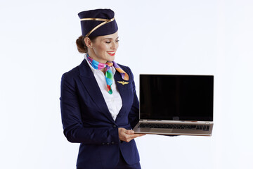 smiling female air hostess on white showing laptop blank screen