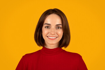Fototapeta premium Portrait of cute young brunette woman on orange studio background