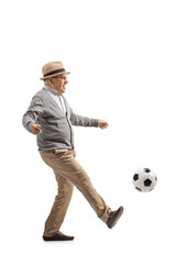 Full length profile shot of an excited elderly man kiciking a football