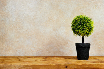 Small artificial tree in a pot on wooden board with copy space 