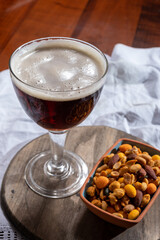 Glass of Belgian abbey red brown beer and glass bowl with party nuts