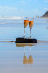 Two glasses of rose champagne or cava sparkling wine served on white sandy tropical beach and blue ocean water, romantic vacation, winter sun on Fuerteventura, Canary, Spain