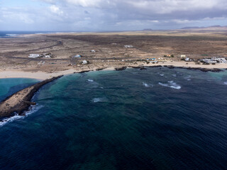 Aerial view on white sandy dunes, blue ocean water on La Concha beach, El Cotillo surfers village, Fuerteventura, Canary islands, Spain