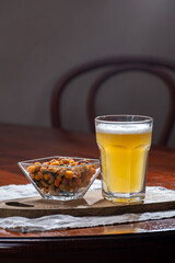 Glass of Belgian white unfiltered beer with notes of coriander and orange peer and different snack nuts