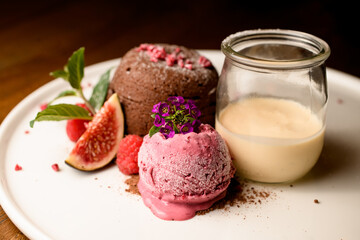 selective focus on ball of ice cream decorated with flower on white plate with chocolate cake