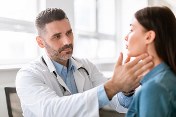 Medicine, healthcare and medical check up concept. Male doctor checking patient's tonsils at...